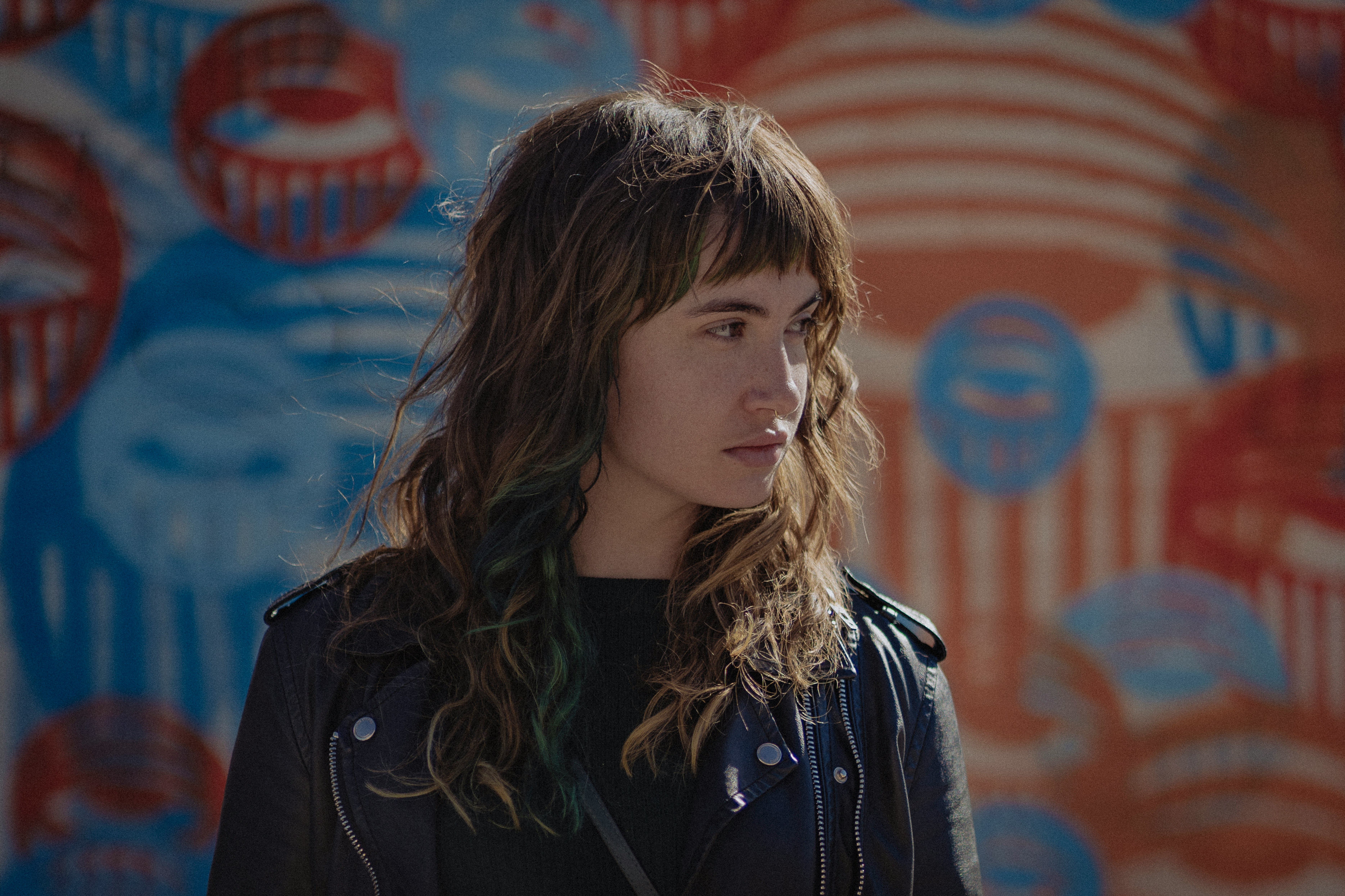 woman in black jacket standing near red and blue wall